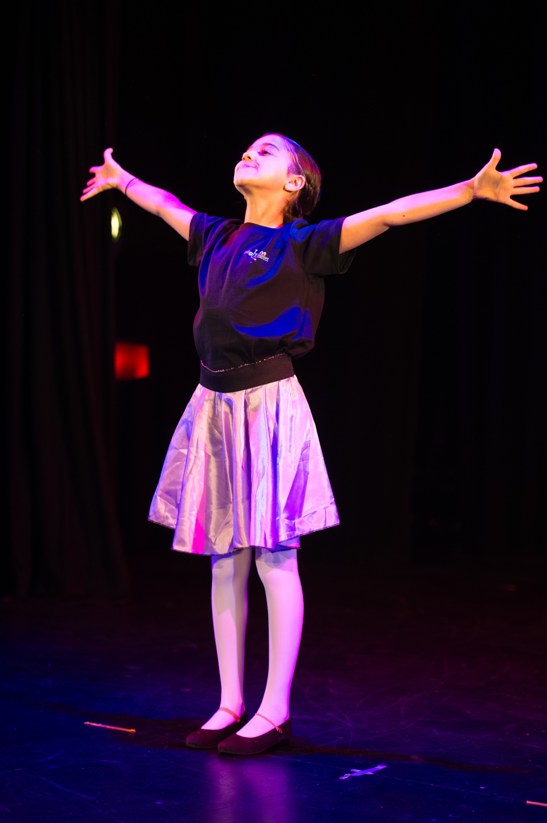 Young performer on stage with arms outstretched